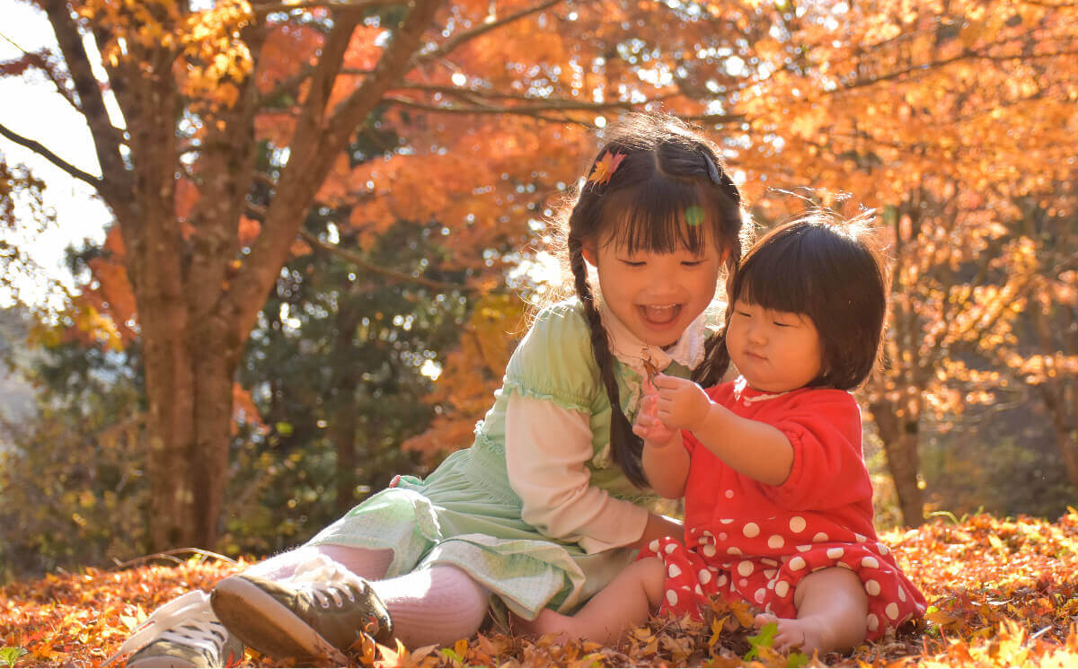 写真：落ち葉で遊ぶ子ども